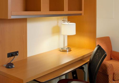 a desk in a room with a lamp and a chair at Hawthorn Extended Stay by Wyndham Cincinnati NE Mason in Mason