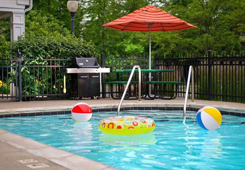 a swimming pool with an umbrella and a ball and an inflatable at Hawthorn Extended Stay by Wyndham Cincinnati NE Mason in Mason