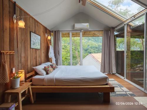a bedroom with a bed in a room with windows at U Garden in Ban Huai Khai