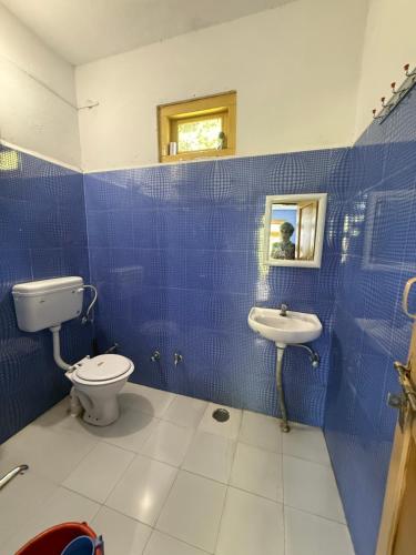 a blue tiled bathroom with a toilet and a sink at The Soul Himalaya in Tosh