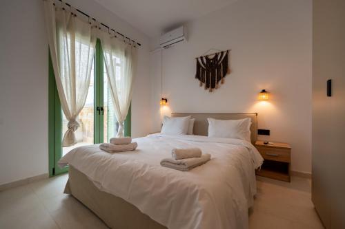 a bedroom with a large white bed with towels on it at Asini deluxe suite 4, with rooftop terrace and breathtaking views in Asíni