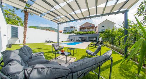 a patio with a couch and chairs under a pergola at Villa Amor in Mostar