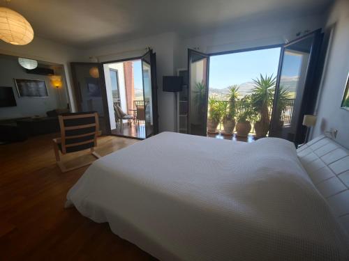 a bedroom with a white bed and a large window at Vistas de Ronda in Ronda