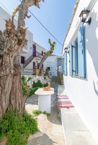 a table next to a tree next to a building at Xenia Xinara in Tinos