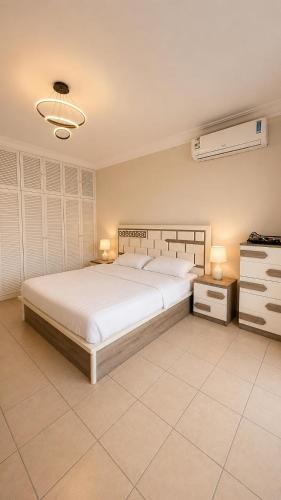 a bedroom with a large white bed and two lamps at شالية البردايس درة العروس من ارقى الشاليهات in Durat Alarous
