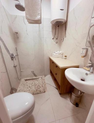 a white bathroom with a toilet and a sink at Mostoliva Sea View Studios in Pržno