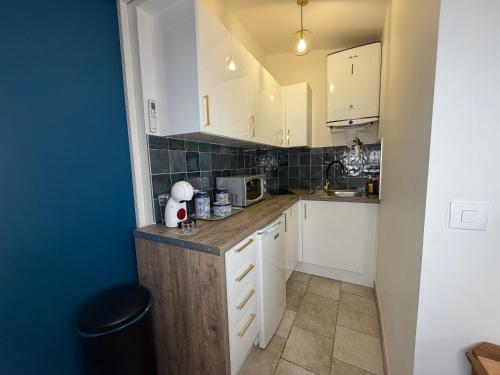 a small kitchen with white cabinets and a counter at Studio moderne climatisé - Parking gratuit - Paris & Disney in Ormesson-sur-Marne