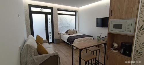 a small room with a bed and a couch and a tv at Alojamientos, BALCÓN A LA SIERRA AHILLOS in Alcaudete