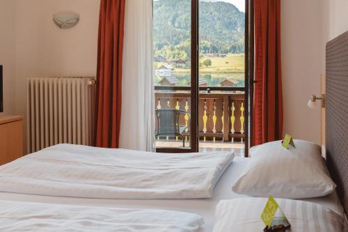 a hotel room with two beds and a balcony at Hotel Lipeter & Bergheimat in Weissensee