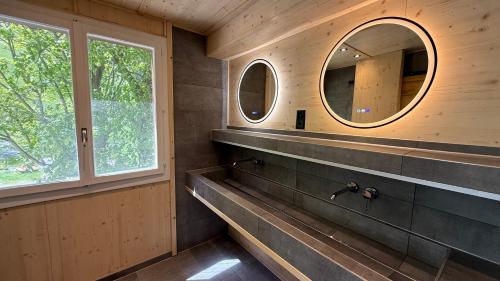 a bathroom with two mirrors and a sink at ALPENHOF Mountain Lodge in Stechelberg