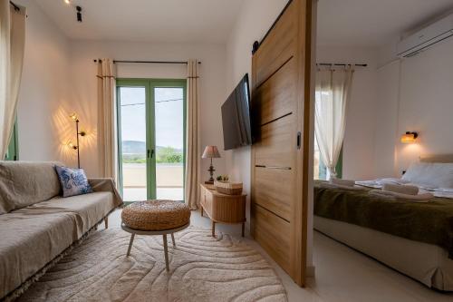 a bedroom with a bed and a couch and a tv at Asini deluxe suite 5, with rooftop terrace and breathtaking views in Asíni