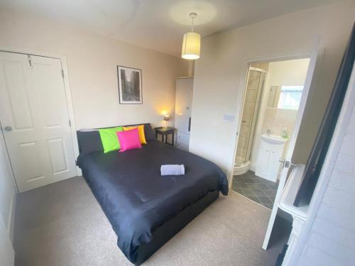 a bedroom with a black bed with colorful pillows at 4-5 Bedroom House For Corporate Stays in Kettering in Kettering
