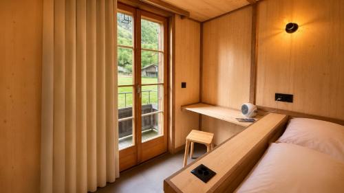 a small bedroom with a bed and a window at ALPENHOF Mountain Lodge in Stechelberg