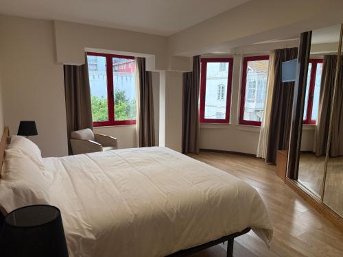 a bedroom with a large white bed and windows at Hotel CHG LEYTON in Foz