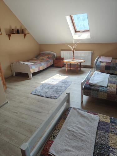a attic room with two beds and a table at Lipowy Dworek Pensjonat in Staroguby