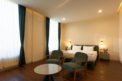 a hotel room with a bed and two chairs and a table at Aanya Taara Resort- Mettupalayam in Mettuppālaiyam