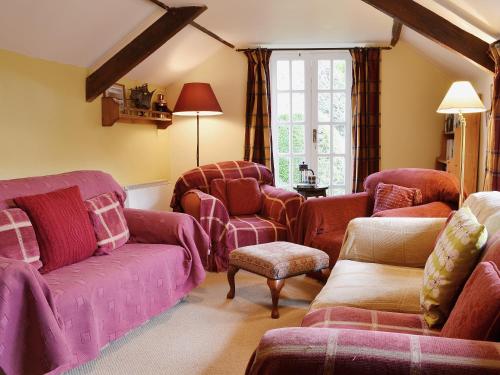 a living room with pink couches and chairs at The Old Barn in Abbotsham
