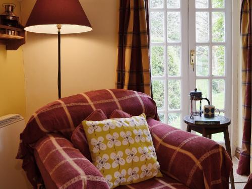 a couch with a pillow in front of a window at The Old Barn in Abbotsham
