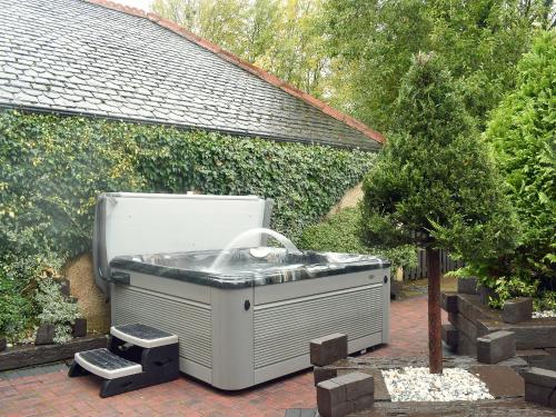 a hot tub sitting in a yard next to a tree at Tennox Farm House - Uk36254 in Kilbirnie