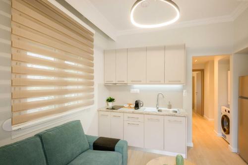a kitchen with white cabinets and a blue couch at Elia Apartments in Ierissos