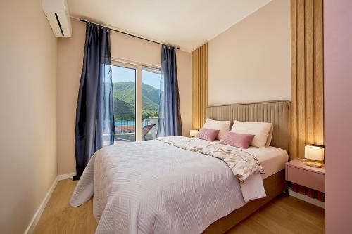 a bedroom with a bed with pink pillows and a window at Boka Bay by MN Property in Dobrota