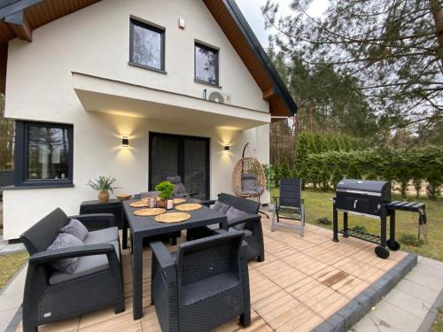 a patio with a table and chairs and a grill at Leśna Przystań Kaszuby in JeleÅ„ska Huta