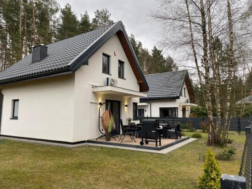 a white house with a black roof at Leśna Przystań Kaszuby in JeleÅ„ska Huta