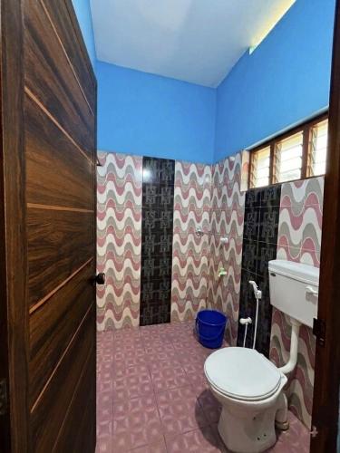 a bathroom with a toilet and a wooden door at CK Enclave in Tripunittura