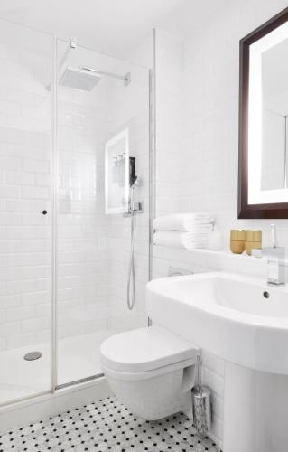 a white bathroom with a toilet and a sink at Plaza Tour Eiffel in Paris