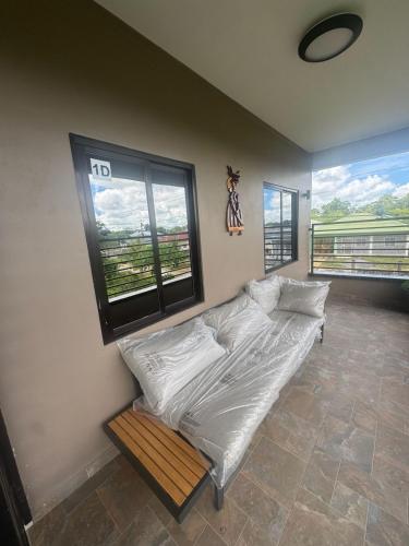 a bed in a room with two large windows at Sisa Omi Apartments in Wanica