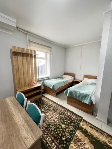 a room with two beds and a table and chairs at Sayak hotel & hostel in Karakol