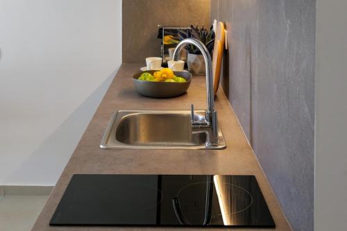 a kitchen counter with a sink and a bowl of fruit at PJ Properties Sunset Residence Sounio in Sounio