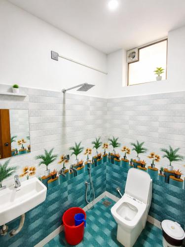 a bathroom with a toilet and plants on the wall at Santa Maria Hostel Kovalam in Kovalam