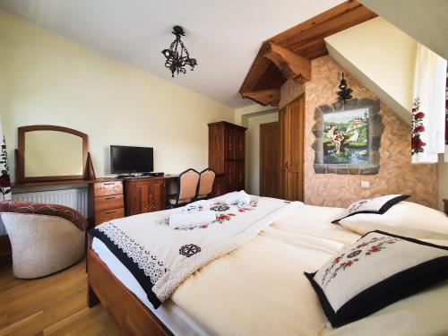 a bedroom with a large bed and a tv at Willa Tatrzański Zomecek in Kościelisko
