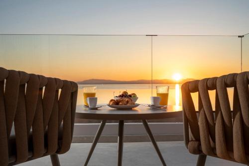 a table with a bowl of food and two chairs at Elysian Beachfront Luxury Suite with Jacuzzi - Sea & City View - ADULTS ONLY in Kos