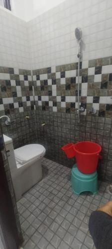 a bathroom with a toilet and a red bucket at Kunjapuri Homestay in Uttarkāshi