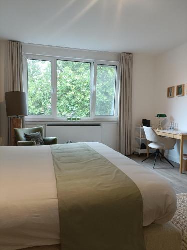 a bedroom with a bed and a desk and windows at B&B Intilia in Kortrijk