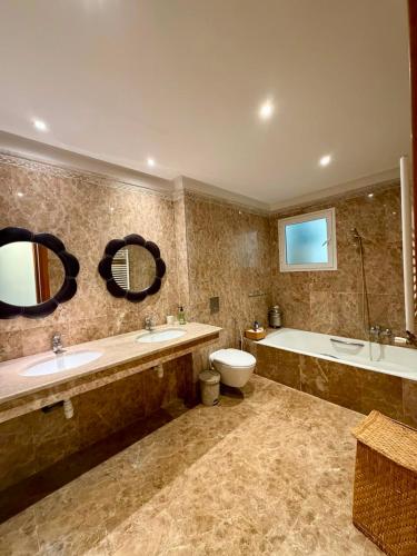 a bathroom with two sinks and a tub and a toilet at Comfy 2Bdrs Marsa in Carthage