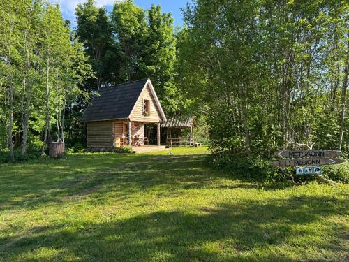 a log cabin in a field with a sign in the yard at Salatse metsaonn in Salatse