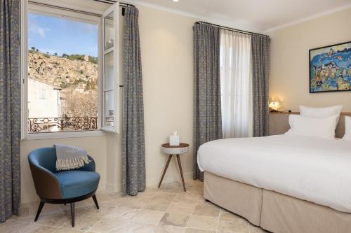 a bedroom with a bed and a chair and a window at LOU CALEN in Cotignac