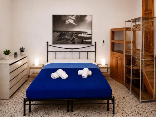 a bedroom with a blue bed with towels on it at Il Giardino su Lido Burrone in Favignana