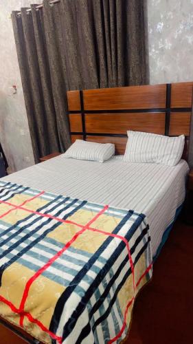 a bed with a striped comforter and two pillows at Prime Stay in Multan