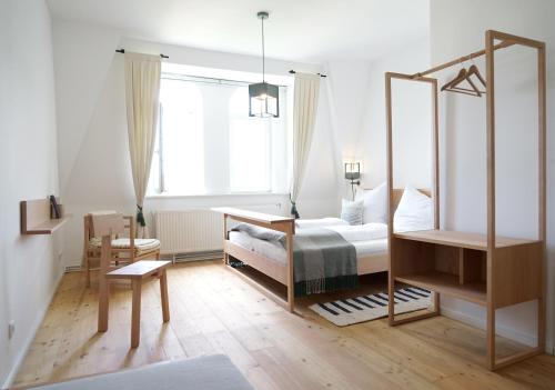 a white bedroom with a bed and a desk at Gut Boltenhof in Fürstenberg