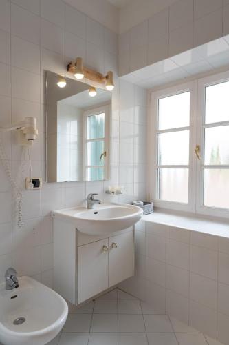 a white bathroom with a sink and a mirror at Naturhotel Wieserhof in Longostagno