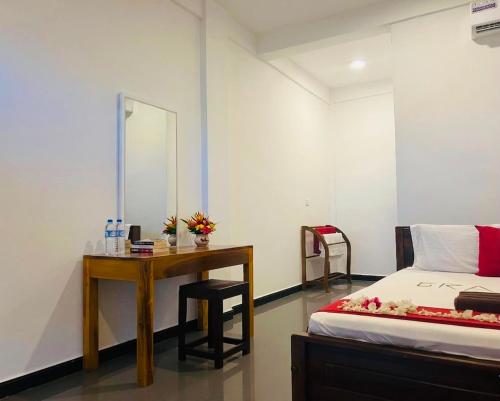 a bedroom with a desk and a bed and a mirror at Grand Bay Hotel in Arugam Bay