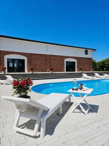 a swimming pool with a white table and chairs next to it at By The Way - domki nad morzem in Paprotno