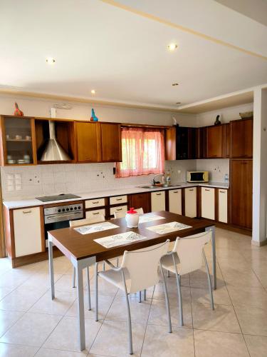 a kitchen with a wooden table and white chairs at Central Moudros apartments in Moúdhros