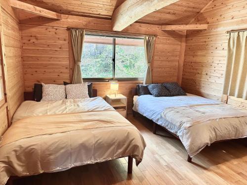 a bedroom with two beds in a log cabin at Lodge Kurokawa 2 Forest in Minamioguni