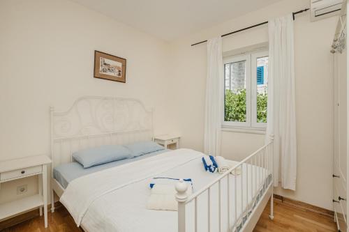a white bedroom with a white bed and a window at Lavender house with shared pool in Herceg-Novi