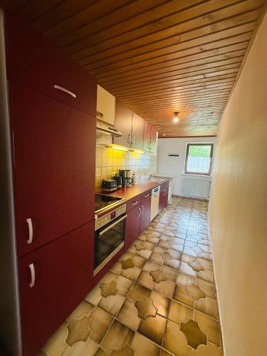 a kitchen with red cabinets and a tile floor at Ferienwohnung Bayerischer Wald in Zwiesel